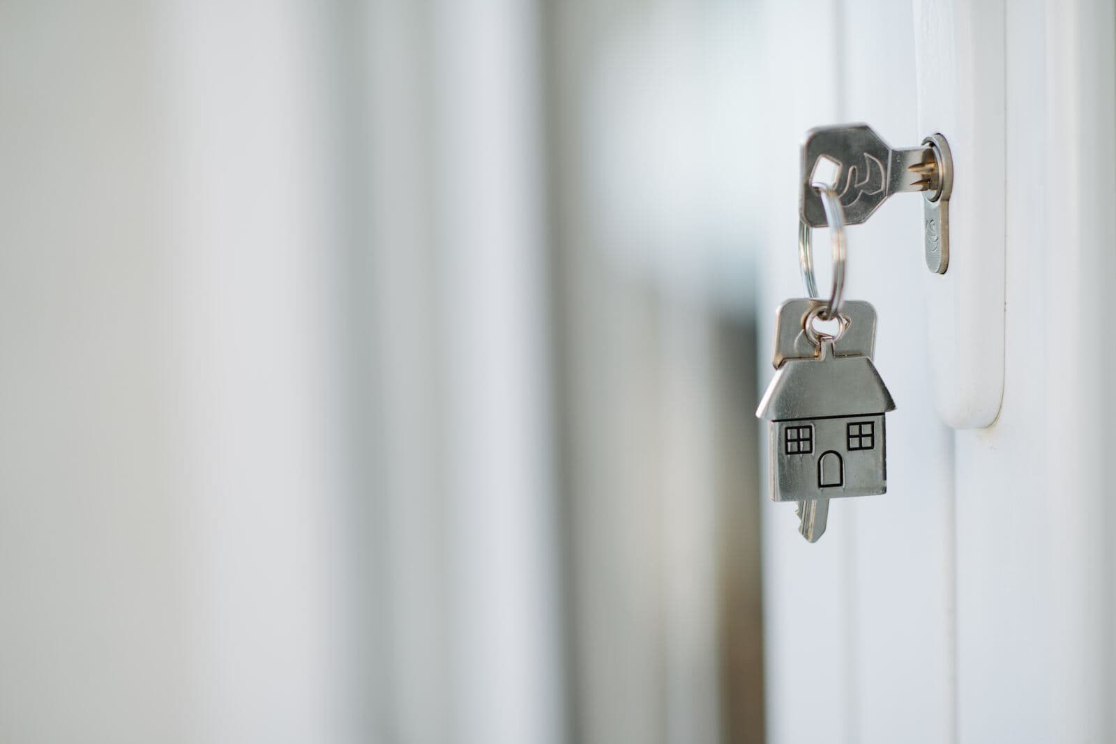 A house-shaped keychain hanging from a key in a front door
