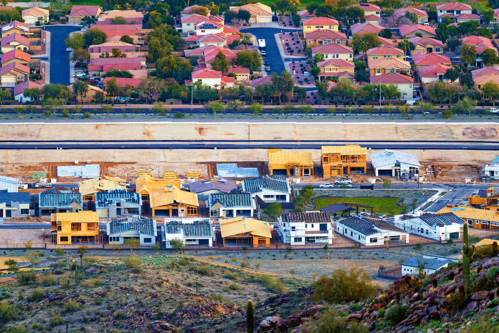 A row of new homes under construction beside a finished neighborhood